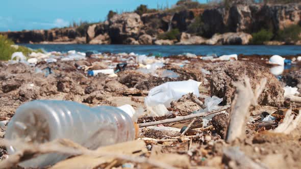 Rack focus on plastic water bottle littered on dirty beach, Closeup