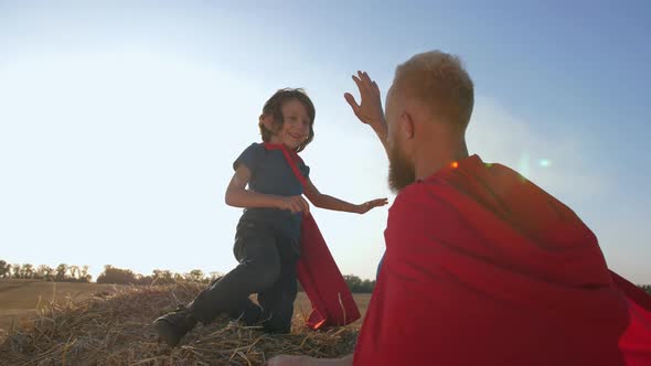 Joyful Boy and Father Pretending To Be Superheroes