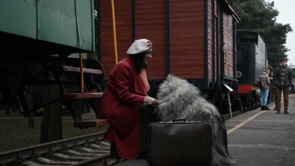 Woman with a Large Dog and Suitcases Waiting for the Train