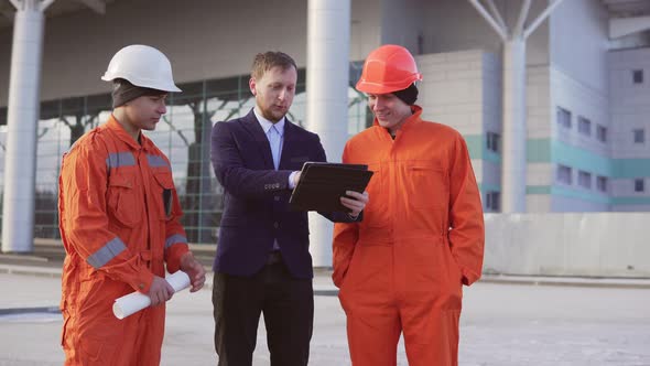 Investor of the Project in a Black Suit Examining the Building Object with Construction Workers in