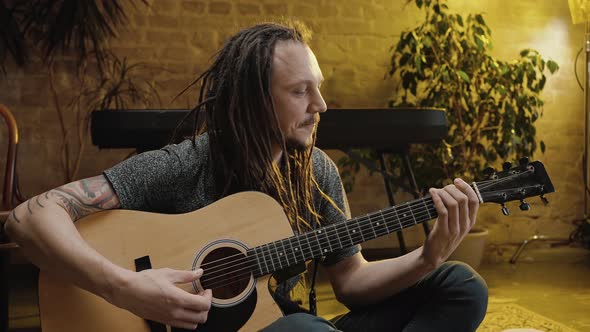 Young Happy Man Musician with Dreadlocks Playing Guitar Rehearsing Before Performance on Stage