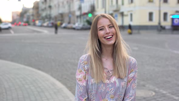 Portrait of European Joyful Woman Wearing Dress Laughing While Walking in Downtown Across Street