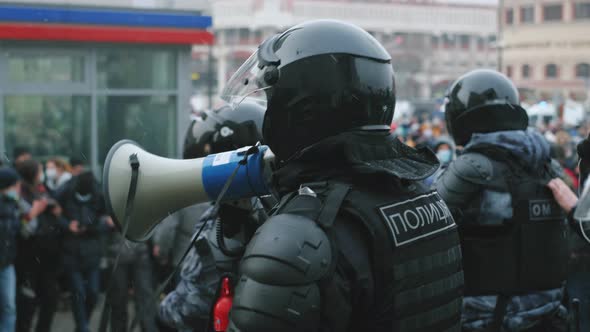 Enforcer in Riot Police Uniform Speaks with Megaphone Bullhorn to Protesters