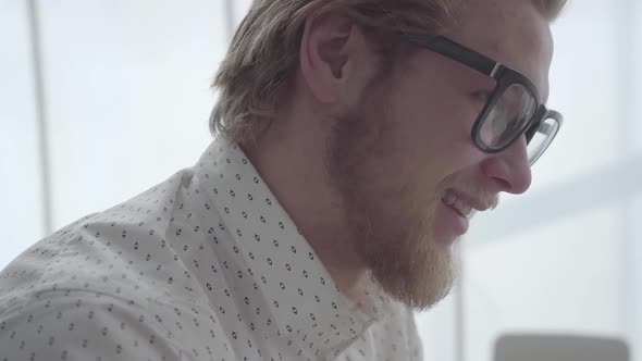 Close Up Face Bearded Businessman in Glasses Sitting in a Light Comfortable Office