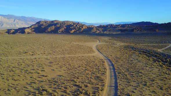 Scenic aerial drone view of dirt road and rocky desert landscape.