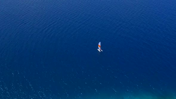 Aerial drone view of a man and woman sailing on a boat to a tropical island