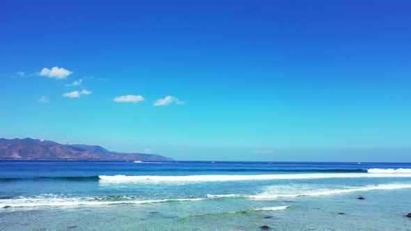 Colorful seascape with white waves foaming over calm turquoise lagoon under bright blue sky backgrou