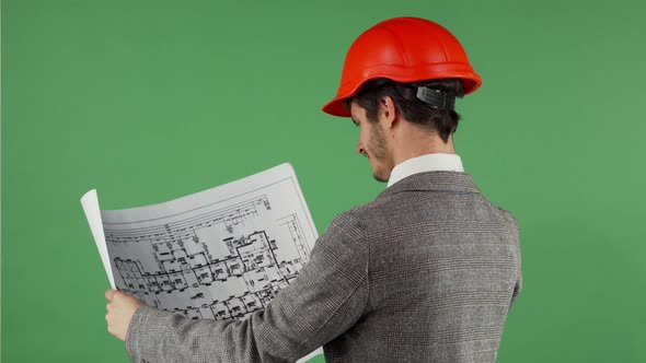 Handsome Bearded Engineer Smiling To the Camera While Examining Blueprints