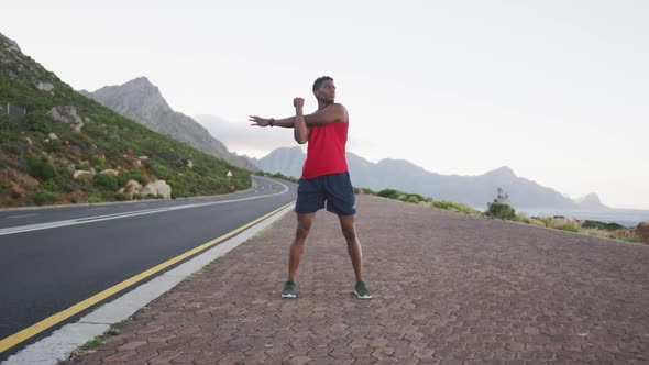 African american man performing stretching his arms while standing on the road