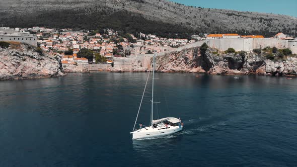 Sailboat floating on sea along coastal town on sunny day