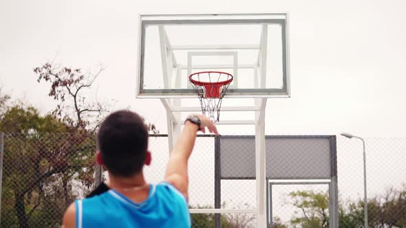 Back View of Unrecognizable Player Throwing Ball in a Basketball Hoop the Ball Hits the Ring and