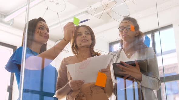 Businesswomen with Pie Chart on Office Glass Board