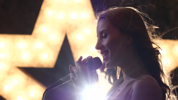 Silhouette Sexy Woman Singer with Microphone, Shining Star in the Background. Close Up, Side View