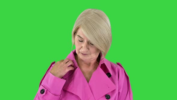 Beautiful Stylish Senior Lady in Trench Coat Posing To Camera on a Green Screen Chroma Key