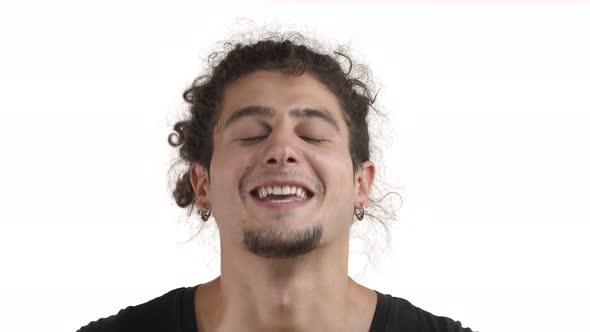 Closeup of Happy Attractive Young Man with Beard Earrings and Curly Ponytail Nodding in Approval