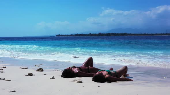 Women best friends on marine seashore beach journey by transparent ocean with white sand background 