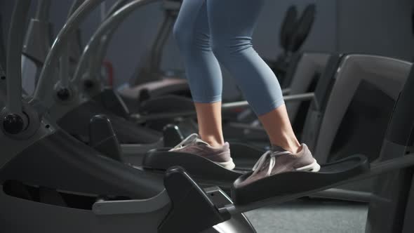 Young Woman Is Working Out on Stepper in a Gym. She Is Walking on Orbitrek for Cardio Intensity and