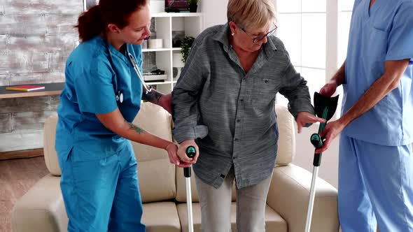 Elderly Woman with Crutches Being Helped By Nurse Team