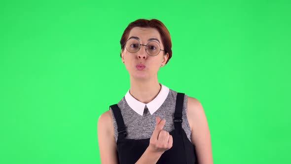 Portrait of Funny Girl in Round Glasses Is Smiling and Showing Heart with Fingers. Green Screen