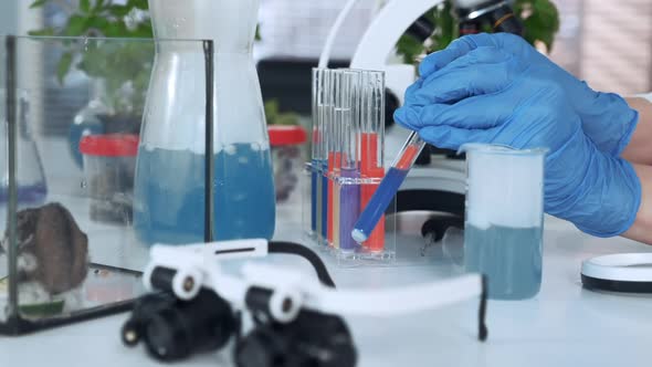 Closeup of Scientist Hands in Lab Gloves Mixing Compounds in Test Tube with Use of Pipette