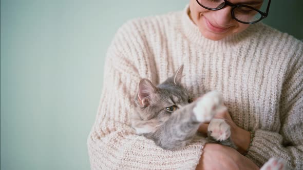 A Woman Petting Her Cute Gray Fluffy Cat While Holding Him in Her Arms