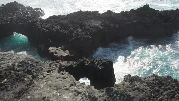 Aerial Footage of a Tourist Walking on the Top of a Lava Rock