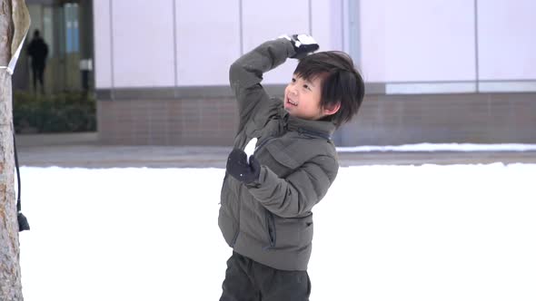 Cute Asian child playing on snow in the park