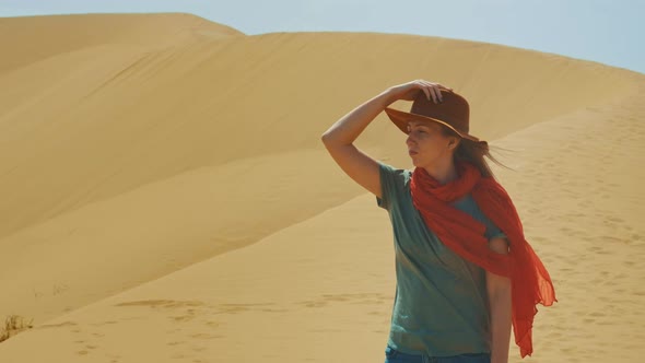 A Young Girl Traveler in a Hat is in the Desert Among the Sands