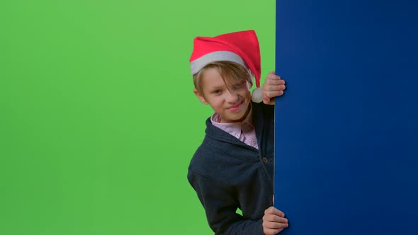 Teen in Christmas Hat Appears From the Side Boards on a Green Screen