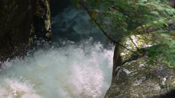 Close up of the spray of a forest waterfall in slow motion.