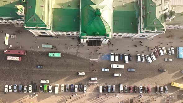 Aerial Footage of Many Cars and Buses Moving on a Busy City Street in Front of Railway Station