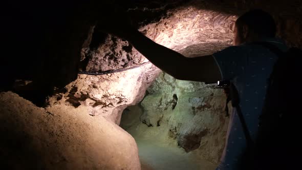 Silhouette of a Man Exploring a Cave with a Torch