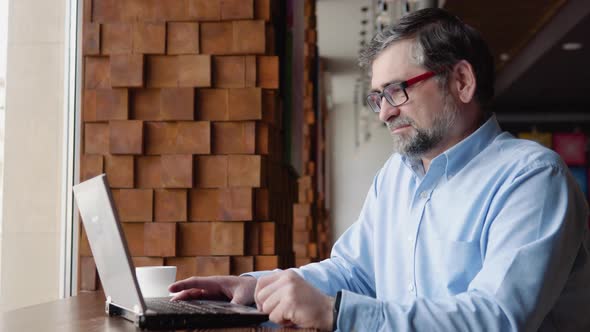 Cheerful Senior Businessman Making Video Conference Online with Client at Remote Workplace