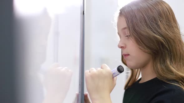 A Little Teenage Girl Goes to School Draws with a Marker on the Blackboard