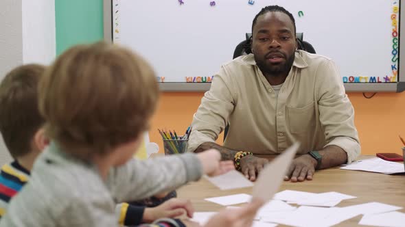 An African American Teacher Teaches a Group of Children Numbers Using Flashcards