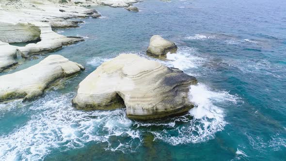 Aerial Top View of Waves Break on Rocks in a Blue Ocean