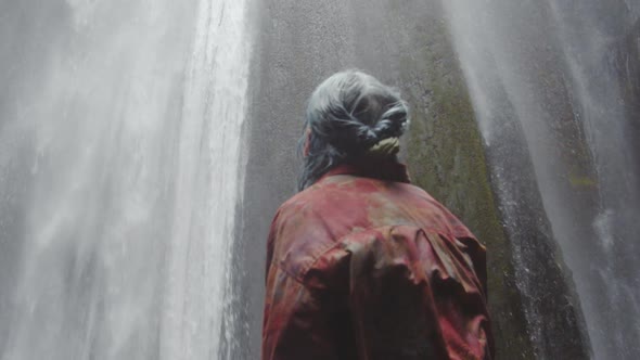 BlueHaired Woman Looking Up At Waterfall