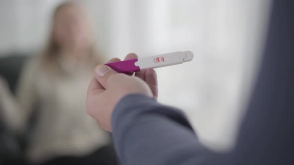 Close-up of Male Caucasian Hand Holding Pregnancy Test with Two Stripes