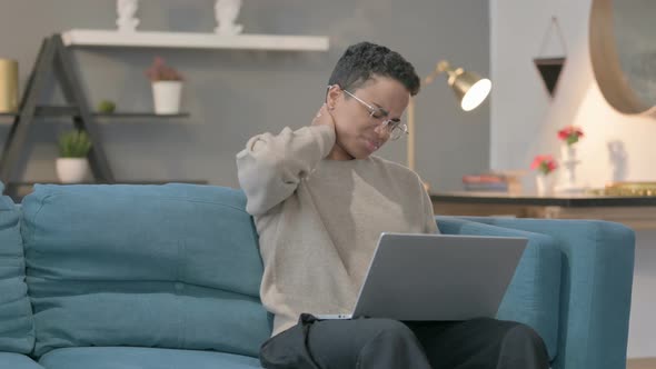 African Woman with Laptop Having Neck Pain on Sofa