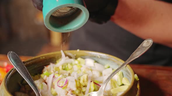 Preparation of Ceviche - slow motion shot capturing the chef seasoning and flavouring the famous per
