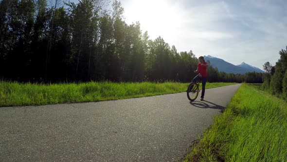 Woman riding unicycle on countryside road 4k