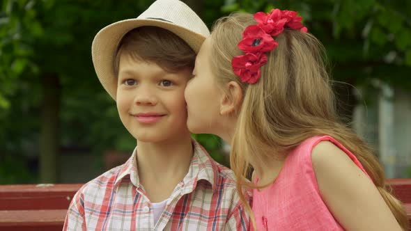 Little Girl Kisses Boy's Cheek on the Bench