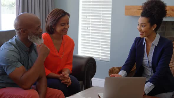Mixed race female real estate agent discussing over property with mature couple on laptop at home 4k