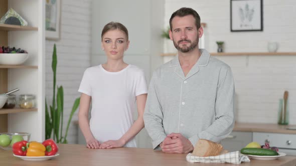 Young Woman and Man Looking at Camera in Kitchen