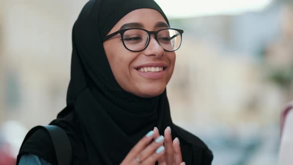 Close-up view of a positive arabian woman wearing national hijab is talking something