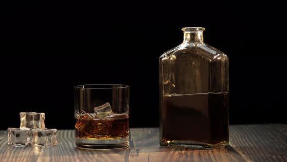 Pouring Whiskey, Cognac Into Glass. Black Background. Pour of Alcohol Drink