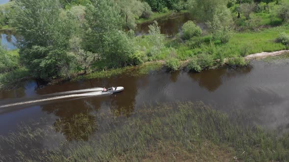 Man on a Motor Boat Floating on a Small Muddy River