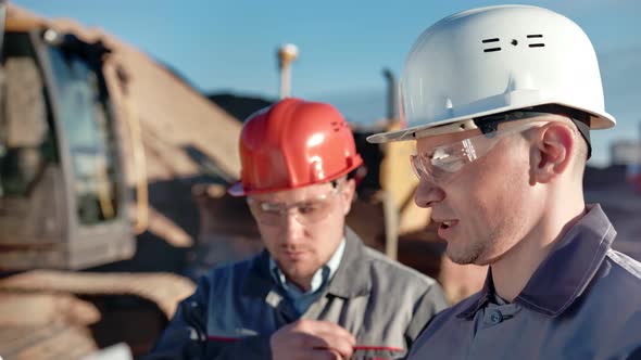 Closeup Two Male Construction Engineer Wearing Helmet and Glasses Discussing Working