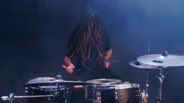 Talented Musician with Dreadlocks Play on Drums in Smoke in a Club