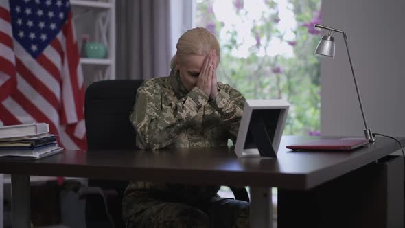 Sad Beautiful Military Woman Sitting at Table Crying Looking at Photo Recalling Memories